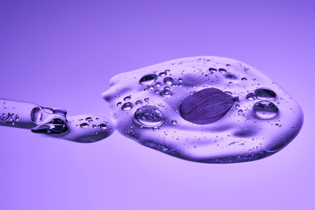 The beautiful texture of the serum with bubbles and a lilac flower pours out of the pipette.の写真素材