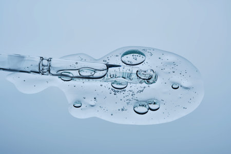 Transparent serum with bubbles and dropper dropper on a blue background.の写真素材