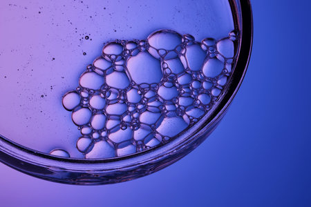 The texture of a cosmetic serum with a trail of bubbles on a purple background.
