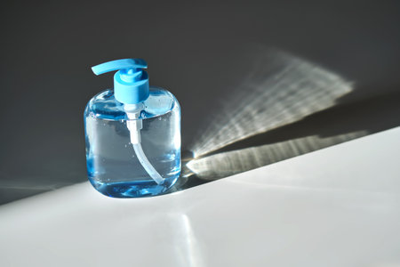 Hand washing gel in a blue bottle with a dispenser on a white background.