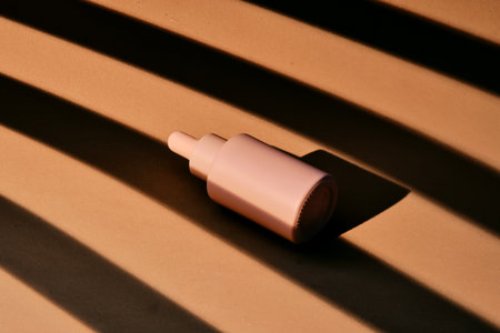 A bottle of serum on a beige background with stripes of shadows.の写真素材