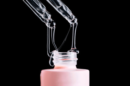 The serum flows beautifully from a pipette onto a pink bottle on a black background.