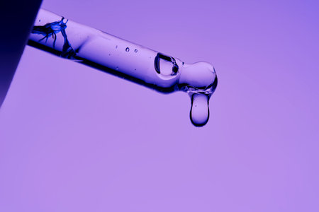 The texture of a cosmetic product with peptides in a pipette on a purple background.の写真素材