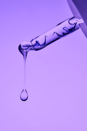 A pipette with serum demonstrating its juicy texture on a purple background.の写真素材