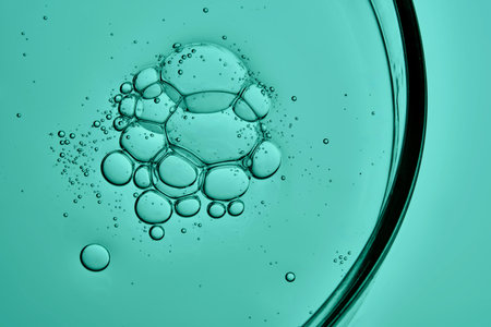 Cosmetic product, serum or shampoo, in a petri dish on a green background.