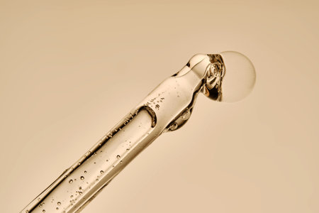 The texture of the serum flowing out of the pipette on a beige background.の写真素材