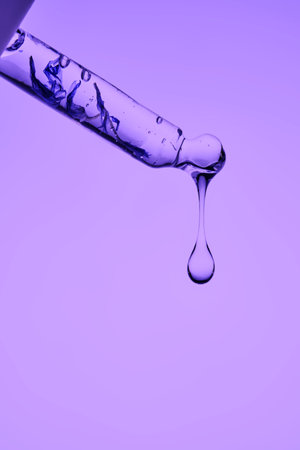A pipette with serum demonstrating its juicy texture on a purple background.の写真素材
