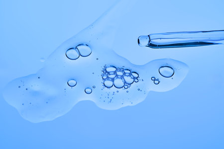 Dropper dropper with cosmetic serum on a blue background.