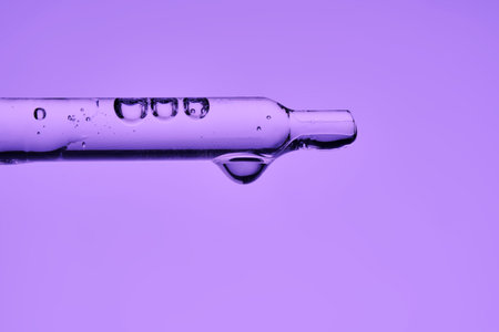 A pipette with serum demonstrating its juicy texture on a purple background.の写真素材