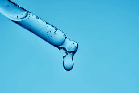 Gel hyaluronic serum in a pipette on a blue background.の写真素材
