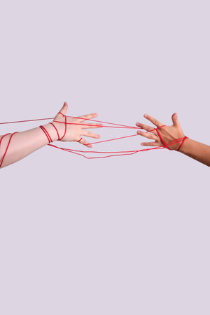 Two hands connected by red string representing destinyの写真素材