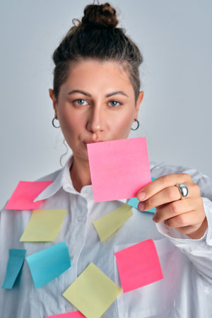 Woman holding sticky note feeling busy and overloadedの写真素材
