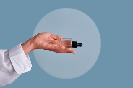 Hand holding dropper bottle with cosmetic serum