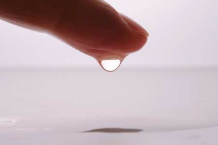 Finger dripping water forming a perfect dropの写真素材