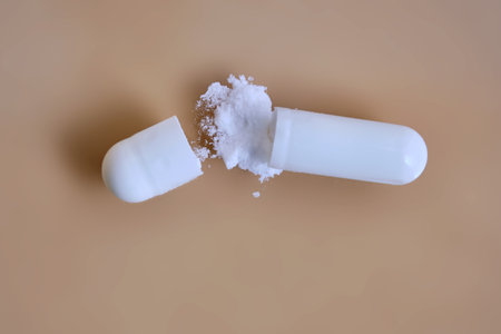 White capsule opening releasing powder medicine on beige background