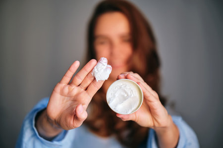 Woman applying beauty cream on fingers for skincareの写真素材
