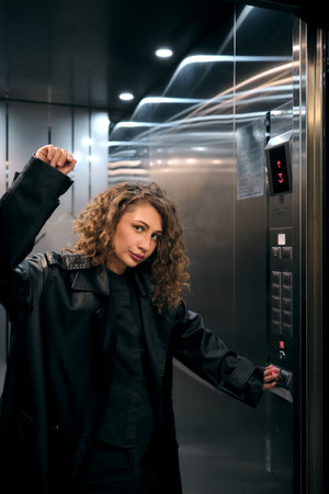 Young woman pressing elevator button in urban settingの写真素材