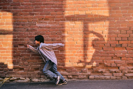 The boy runs away from the shadow on the wallの写真素材