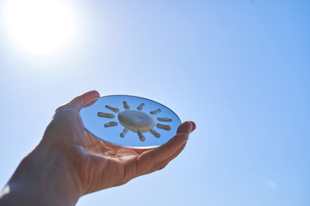 Hand holding mirror reflecting sunscreen sun protectionの写真素材