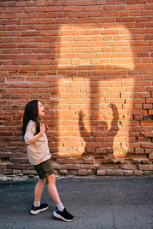 Girl playing shadow games on brick wallの写真素材