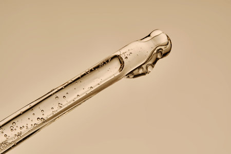 The texture of the serum flowing out of the pipette on a beige background.の写真素材
