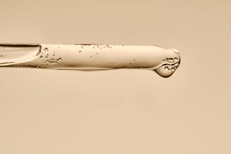 The texture of the serum flowing out of the pipette on a beige background.の写真素材