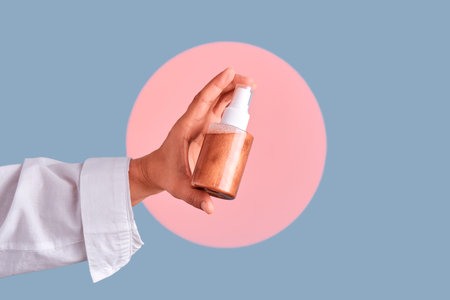 Hand holding spray bottle with bronzer cosmeticsの写真素材