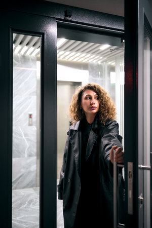 Woman with curly hair opening modern elevator door