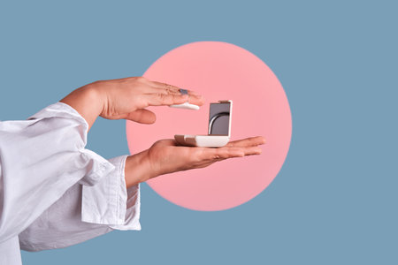 Hands applying face powder from compact caseの写真素材
