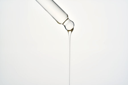 Cosmetic pipette dropping liquid serum oil on white backgroundの写真素材