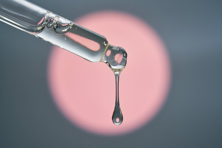 Cosmetic pipette dispensing serum creating a single dropの写真素材