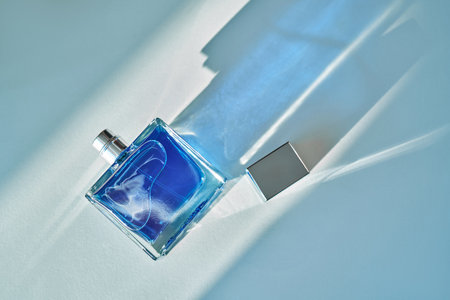 Blue perfume bottle on light background with shadowの写真素材