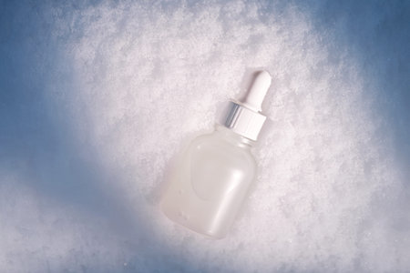 Skincare serum bottle with pipette on snow