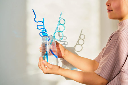 Child holding glass with water and creative straws