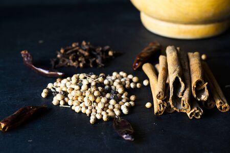 Cinnamon, pepper, cloves and callena. Set of spices on a black slate plateの写真素材