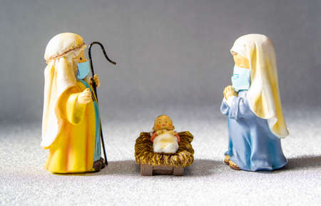 Figures of Saint Joseph, the Virgin Mary and the newborn baby Jesus with hygienic masks. Christmas with the Covid-19 pandemicの写真素材