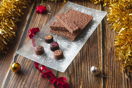 Turron is a typical Christmas food in Spain. This one is made with chocolate and puffed rice. There are also chocolate bonbons with blackberries, hazelnuts and almonds. Horizontal plane and copy spaceの写真素材