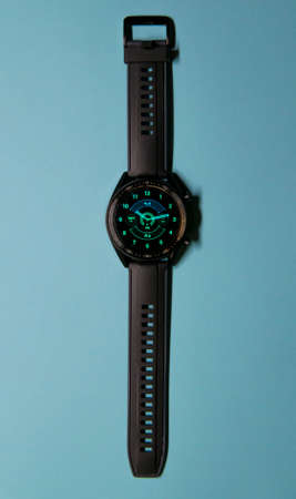 Close up of a black smartwatch on a blue background, similar to a watch face. Technology and elegance concept. Vertical photography. Copy spaceの写真素材