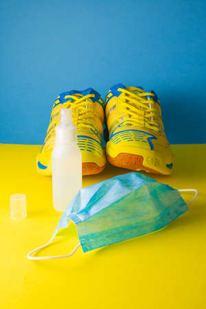 Overhead shot of fitness shoes, surgical mask and hydroalcoholic gel on  blue and yellowの写真素材