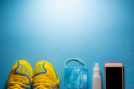 Overhead shot of fitness shoes, surgical mask and hydroalcoholic gel on  blueの写真素材