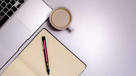 Overhead shot of a workspace from home: laptop, notebook, pen and a cup of coffee. Work from home concept. Copy Spaceの写真素材