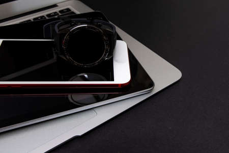 Close-up of a smartwatch, smartphone, tablet and laptop on black background. Wireless technology concept. Horizontal photography. Copyspaceの写真素材