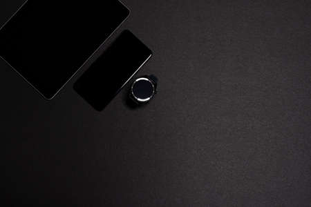 Overhead shot of a smartwatch, smartphone and a tablet on a black background. Wireless technology concept. Horizontal photography. Copyspaceの写真素材