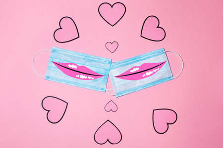 Aerial view of two surgical masks with several red hearts. Valentine's Day concept and new normal for COVID-19 and love gay. Horizontal photography and copy spaceの写真素材