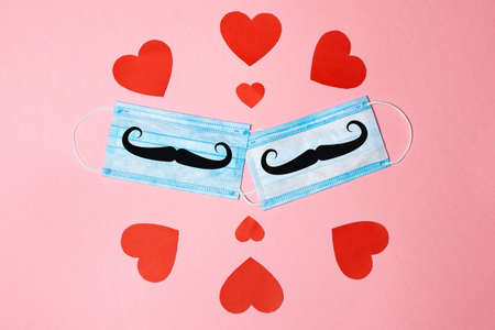 Aerial view of two surgical masks with several red hearts. Valentine's Day concept and new normal for COVID-19 and love gay. Horizontal photography and copy spaceの写真素材