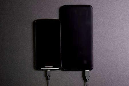 Smartphone connected to a power bank. Way to charge the battery of a mobile phone without connecting to electricity. Tools for telecommunting. Concept wireless technologyの写真素材
