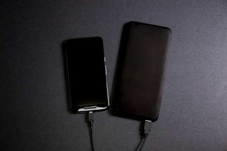 Smartphone connected to a power bank. Way to charge the battery of a mobile phone without connecting to electricity. Tools for telecommunting. Concept wireless technologyの写真素材