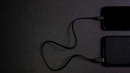 Smartphone connected to a power bank. Way to charge the battery of a mobile phone without connecting to electricity. Tools for telecommunting. Concept wireless technologyの写真素材