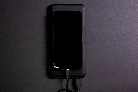 Smartphone connected to a power bank. Way to charge the battery of a mobile phone without connecting to electricity. Tools for telecommunting. Concept wireless technologyの写真素材