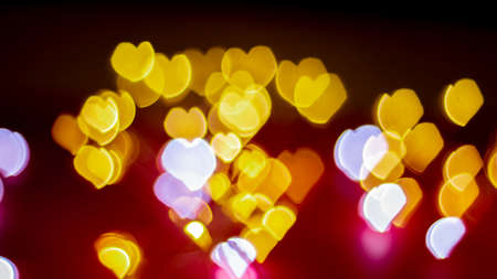 Background of different colors defocused lights with a heart shape on a red background. Abstract image. Valentine, love and passion conceptの写真素材